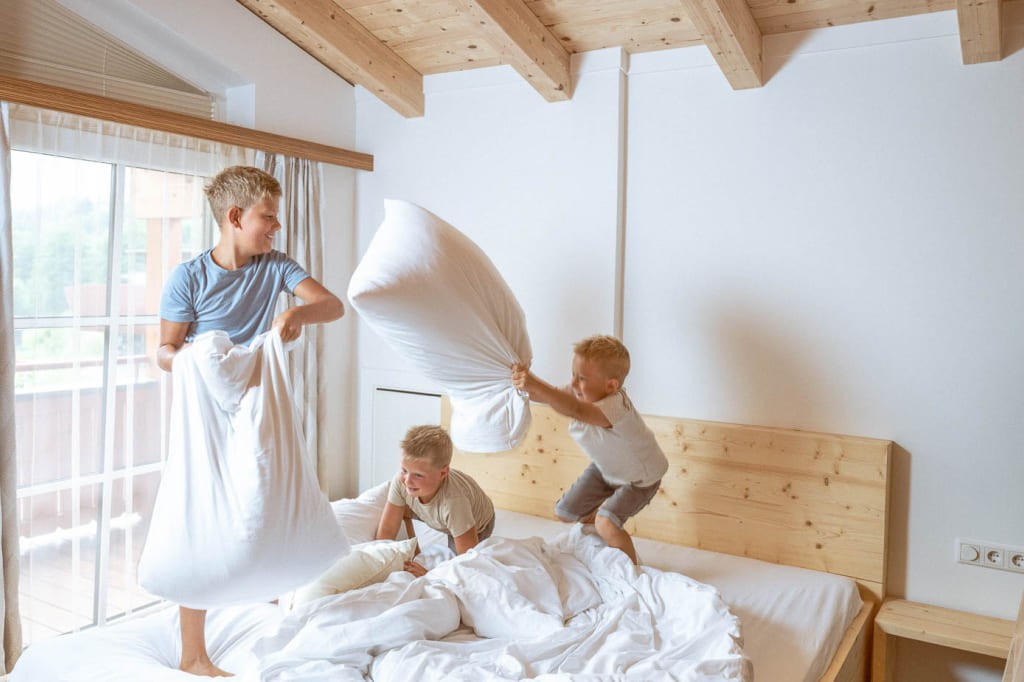 drei Jungen haben Spaß bei einer Kissenschlacht im Bett