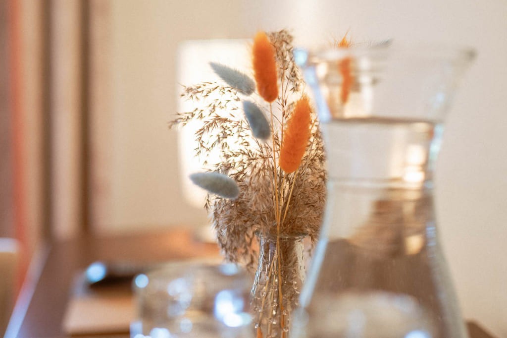 Vase mit orange, blauen Dekogräsern in einem Hotelzimmer