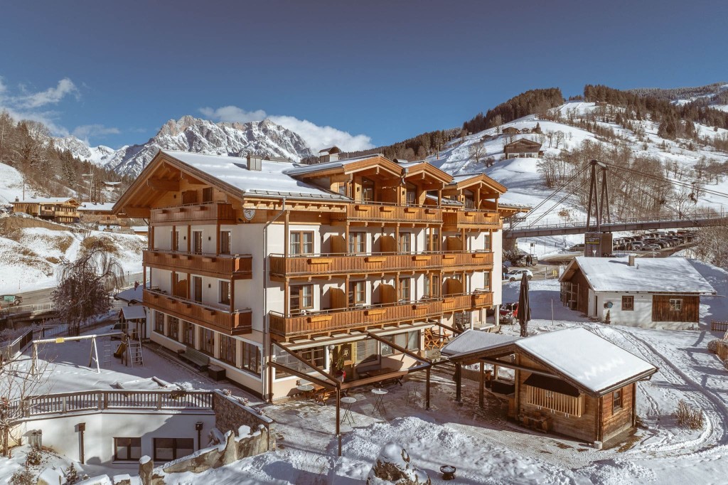Verschneites Hotel Bachschmied in Maria Alm vor blauem Himmel und Bergkulisse