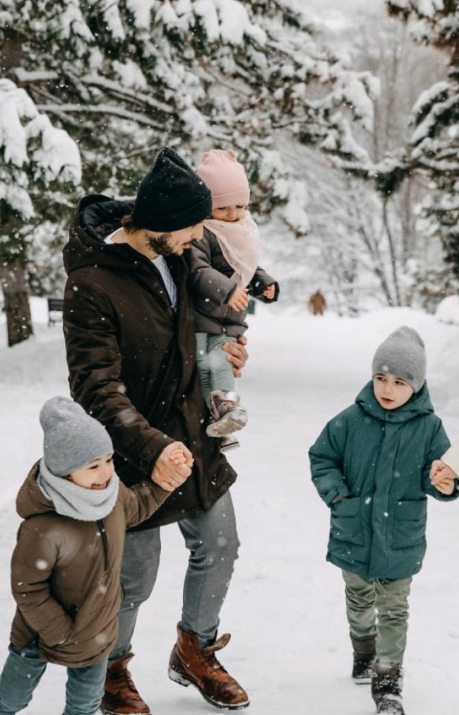 Eine Familie spaziert fr&ouml;hlich im verschneiten Wald im Familienurlaub im Hotel Bachschmied. &copy; Shutterstock